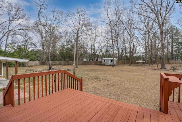 wooden deck with a fenced backyard, a shed, a yard, and an outdoor structure