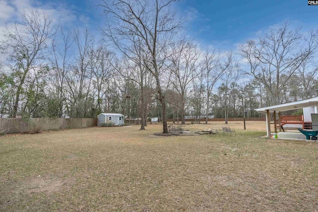 view of yard featuring a storage unit, an outdoor structure, and fence