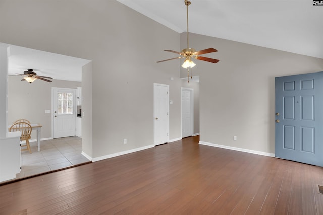 unfurnished living room with baseboards, wood finished floors, high vaulted ceiling, and ceiling fan