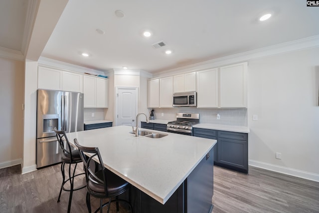 kitchen with ornamental molding, decorative backsplash, stainless steel appliances, white cabinets, and a sink