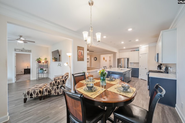 dining area featuring baseboards, light wood-style flooring, crown molding, and ceiling fan with notable chandelier