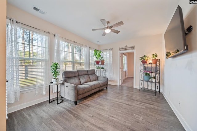 living room featuring visible vents, baseboards, ceiling fan, and wood finished floors