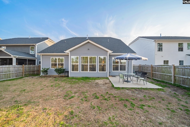 rear view of property with a yard, a patio area, and a fenced backyard