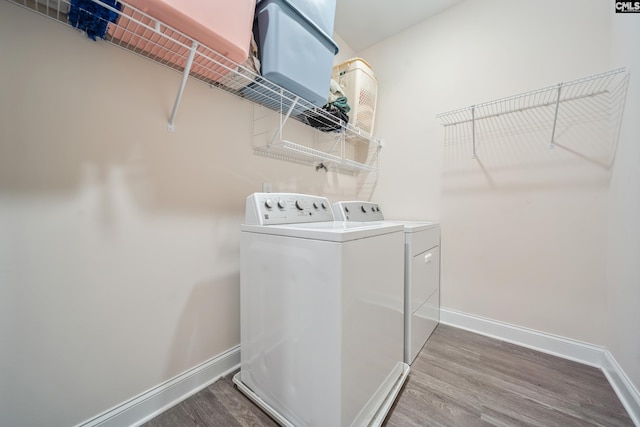 clothes washing area with laundry area, wood finished floors, baseboards, and independent washer and dryer