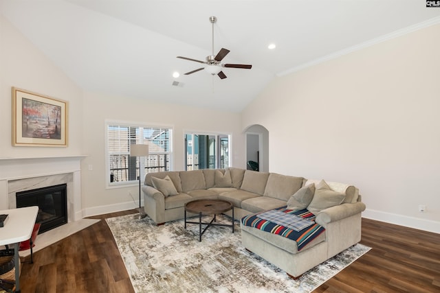 living room featuring arched walkways, dark wood finished floors, baseboards, and a ceiling fan