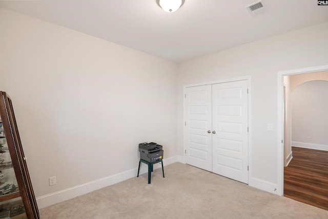 unfurnished bedroom featuring visible vents, baseboards, a closet, carpet flooring, and arched walkways