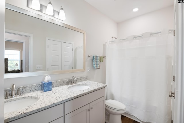 full bathroom featuring curtained shower, double vanity, toilet, and a sink