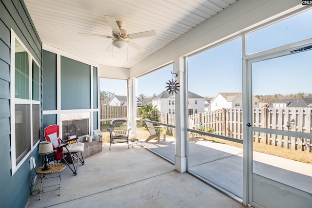 sunroom featuring a ceiling fan, a residential view, and a wealth of natural light