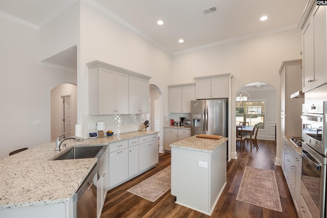 kitchen with visible vents, dark wood-type flooring, a sink, arched walkways, and appliances with stainless steel finishes