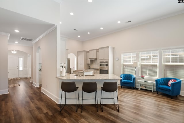 kitchen with light stone counters, visible vents, backsplash, and a breakfast bar