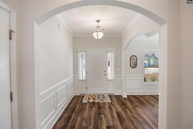 foyer featuring wainscoting, arched walkways, dark wood-style flooring, and ornamental molding