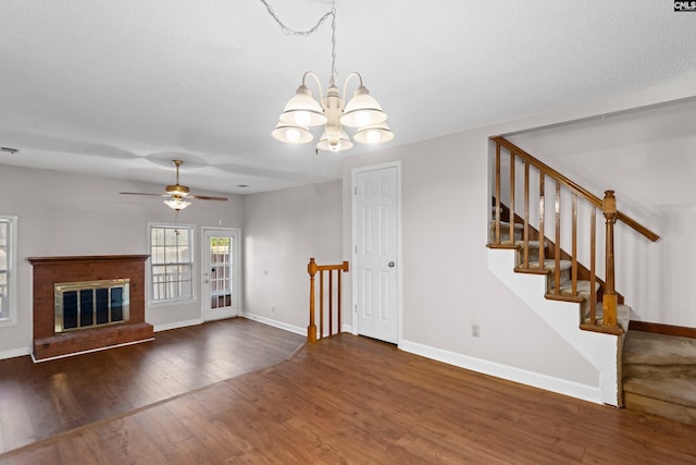 unfurnished living room with ceiling fan with notable chandelier, visible vents, wood finished floors, and baseboards