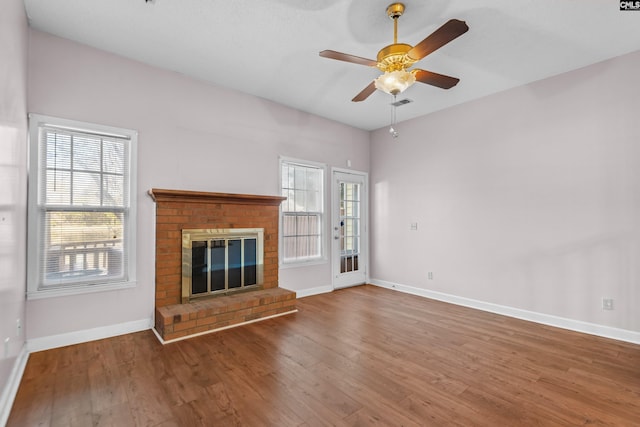 unfurnished living room featuring ceiling fan, baseboards, wood finished floors, and a fireplace