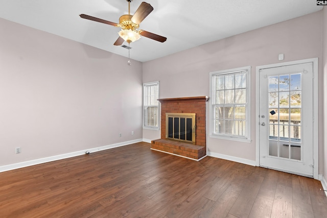 unfurnished living room featuring baseboards, wood-type flooring, a brick fireplace, and ceiling fan