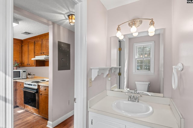 bathroom featuring wood finished floors, visible vents, electric panel, a textured ceiling, and toilet