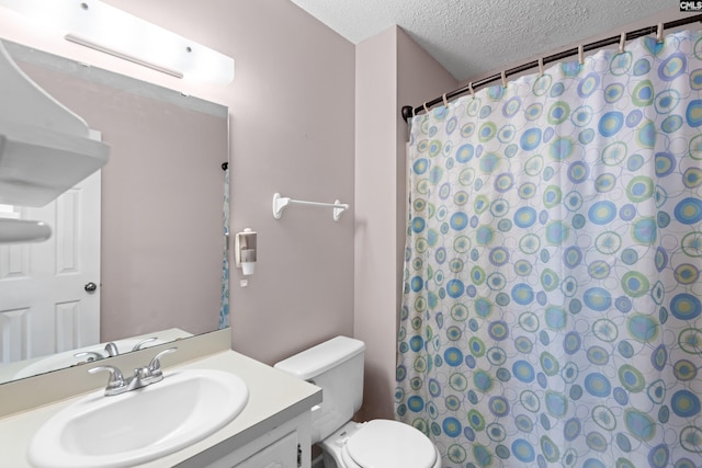 bathroom with vanity, curtained shower, toilet, and a textured ceiling