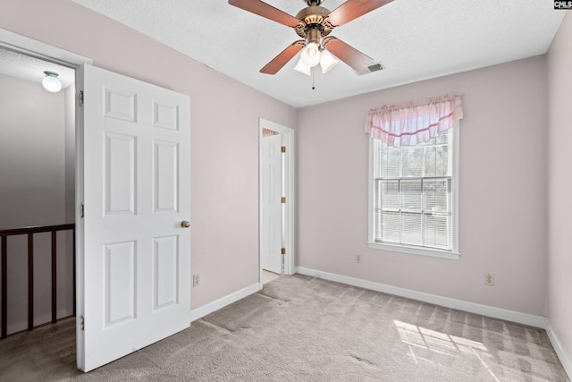 unfurnished bedroom featuring visible vents, baseboards, carpet, a textured ceiling, and a ceiling fan