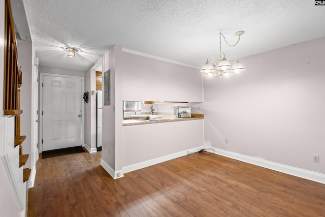 kitchen with a notable chandelier, electric panel, wood finished floors, and baseboards