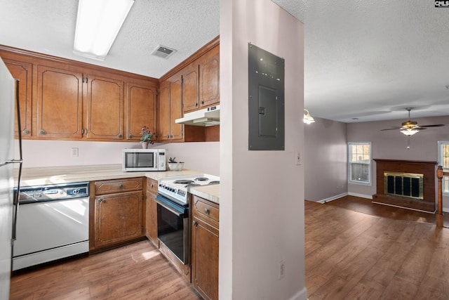 kitchen featuring visible vents, under cabinet range hood, electric panel, brown cabinets, and stainless steel appliances