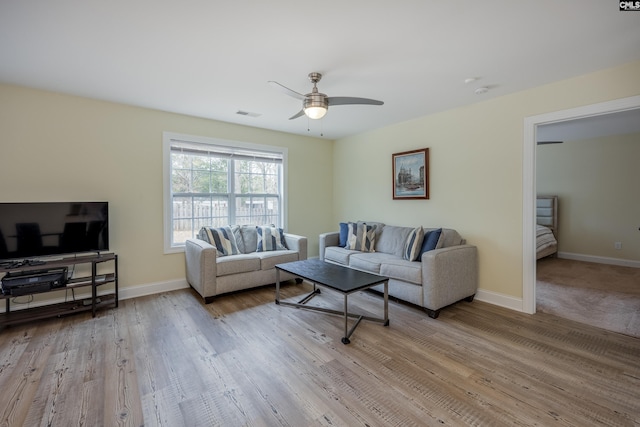 living area with visible vents, baseboards, a ceiling fan, and wood finished floors