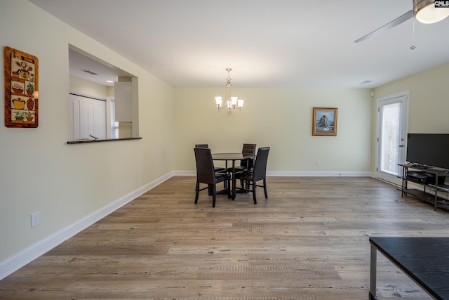 dining room featuring visible vents, baseboards, wood finished floors, and ceiling fan with notable chandelier