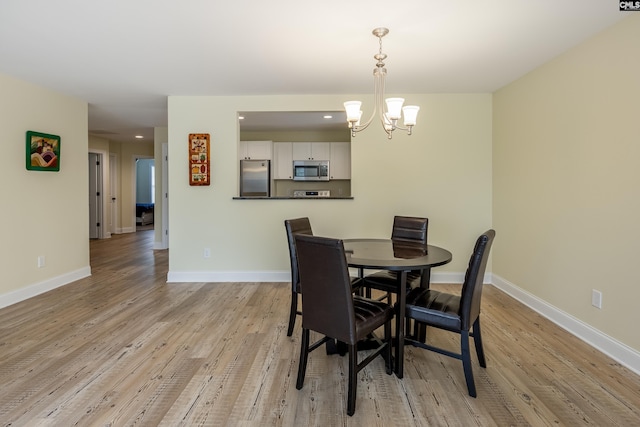 dining room featuring baseboards, light wood-type flooring, and an inviting chandelier