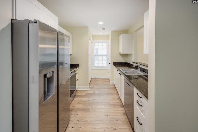 kitchen with light wood-style flooring, appliances with stainless steel finishes, white cabinetry, and a sink