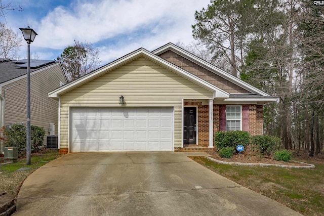 single story home with brick siding, an attached garage, central AC unit, and driveway