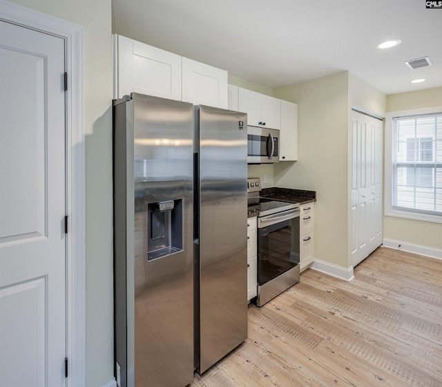 kitchen featuring visible vents, white cabinetry, stainless steel appliances, light wood-style floors, and baseboards