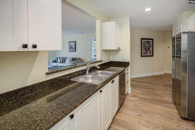 kitchen featuring a sink, white cabinetry, stainless steel appliances, light wood-style floors, and baseboards