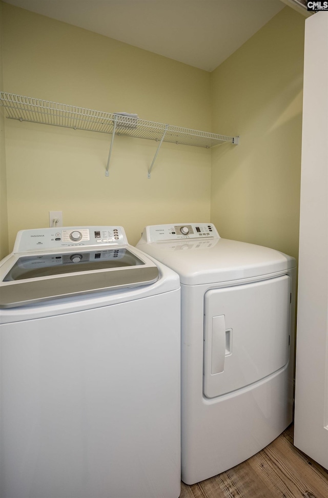 clothes washing area featuring laundry area, washing machine and dryer, and wood finished floors