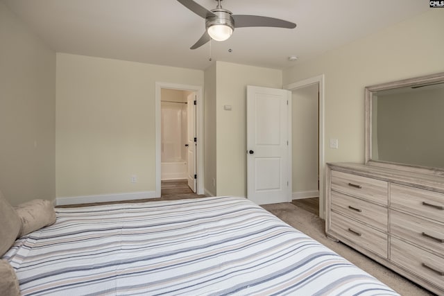 bedroom with light carpet, a ceiling fan, ensuite bathroom, and baseboards