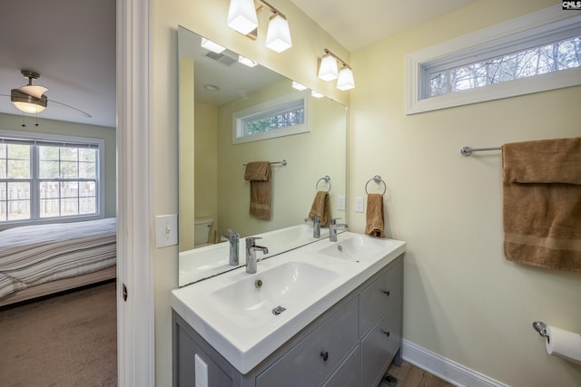 bathroom featuring ceiling fan, double vanity, baseboards, and a sink