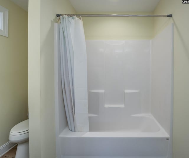 bathroom featuring toilet and shower / tub combo with curtain