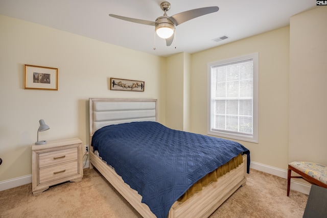 bedroom featuring visible vents, light colored carpet, a ceiling fan, and baseboards