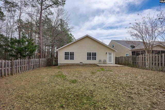 rear view of property featuring a yard, a patio, and a fenced backyard