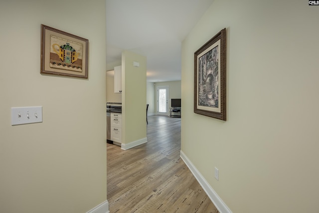 hallway featuring light wood-style flooring and baseboards