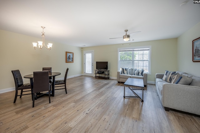 living area with light wood-style flooring, ceiling fan with notable chandelier, and baseboards