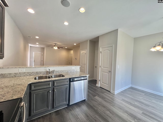 kitchen featuring baseboards, a peninsula, a sink, dark wood-type flooring, and appliances with stainless steel finishes