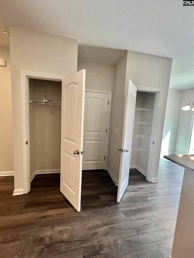 unfurnished bedroom featuring a closet, baseboards, and dark wood-style flooring