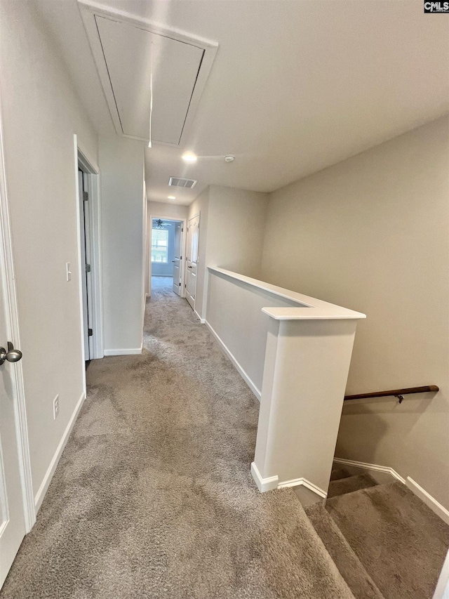 hallway featuring visible vents, carpet floors, baseboards, attic access, and an upstairs landing