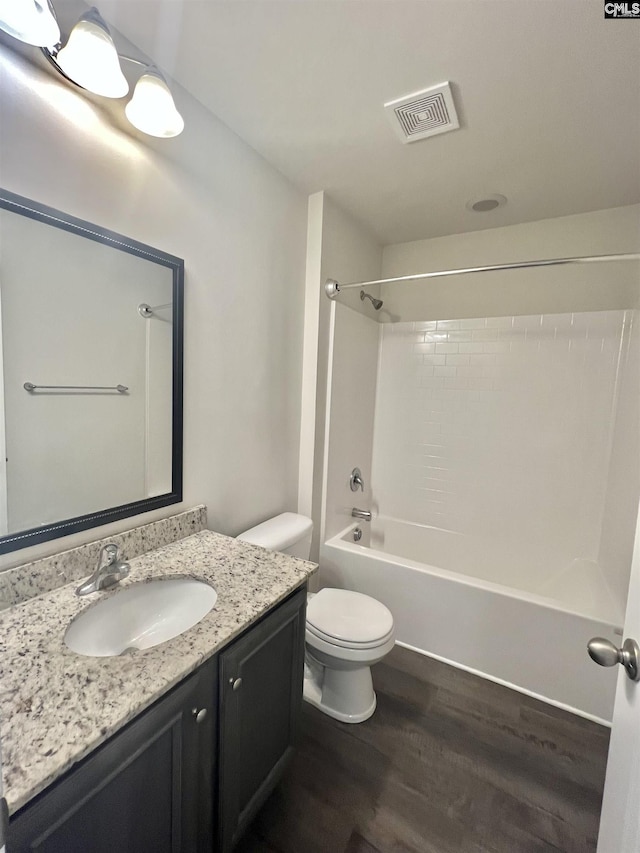 full bathroom with visible vents, toilet, wood finished floors, vanity, and shower / bathtub combination