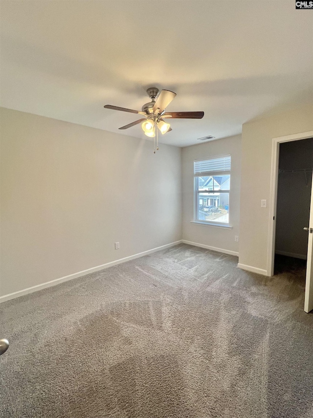 carpeted spare room featuring visible vents, baseboards, and ceiling fan