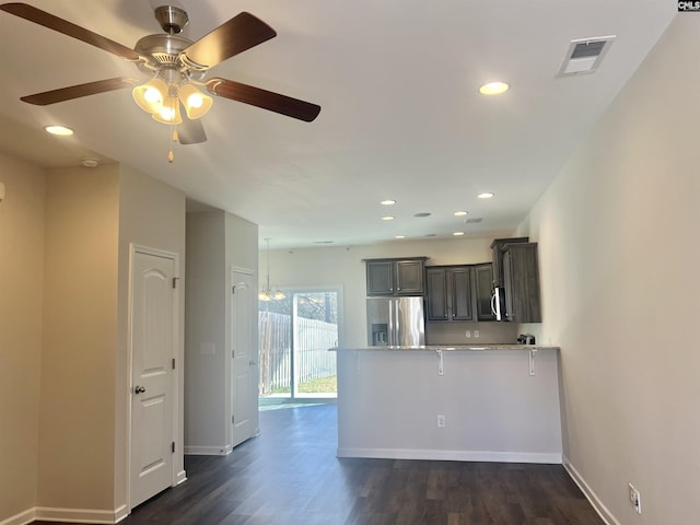 kitchen with visible vents, a peninsula, ceiling fan, dark wood-type flooring, and appliances with stainless steel finishes