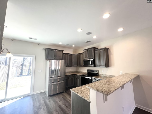 kitchen with visible vents, dark wood finished floors, light stone counters, appliances with stainless steel finishes, and a peninsula