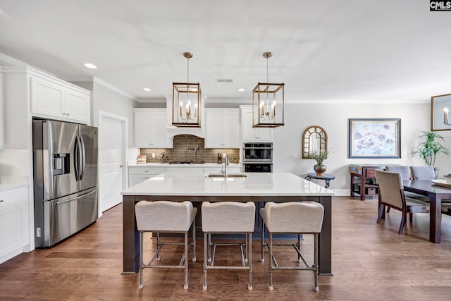 kitchen with a sink, light countertops, decorative backsplash, appliances with stainless steel finishes, and dark wood-style flooring