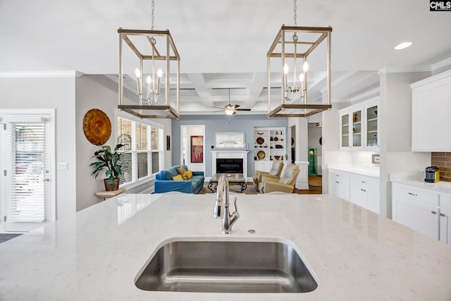 kitchen featuring a fireplace, light stone countertops, coffered ceiling, and a sink