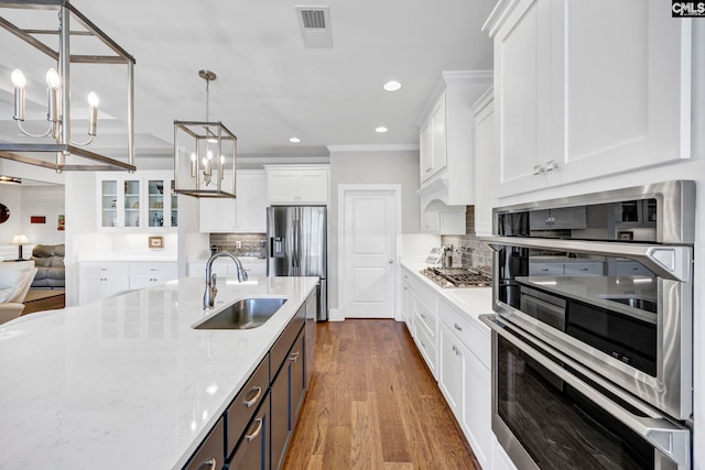 kitchen featuring decorative backsplash, white cabinetry, stainless steel appliances, and a sink