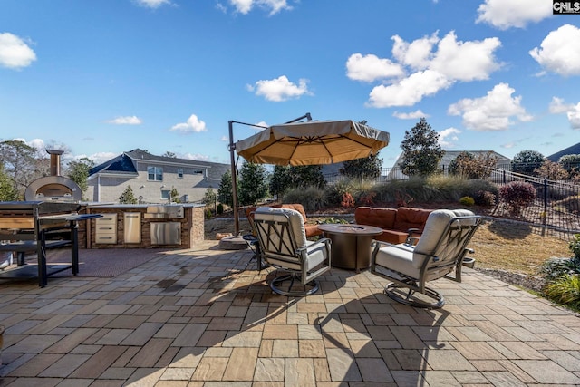 view of patio / terrace with grilling area, a fire pit, fence, and an outdoor kitchen