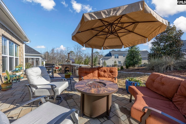 view of patio with an outdoor living space with a fire pit, exterior kitchen, and fence